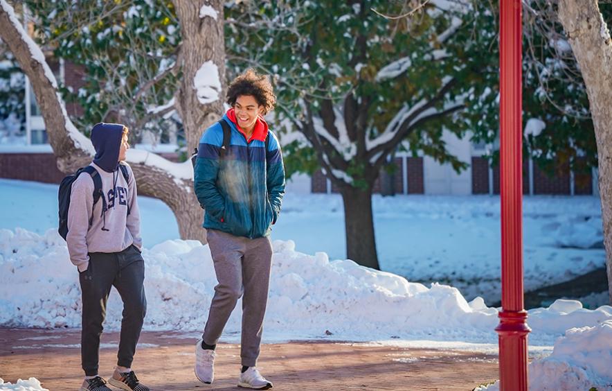two students walking on campus with snow in background